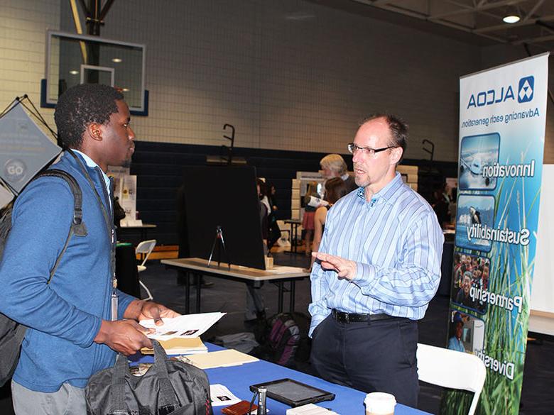 A corporate recruiter meets with an individual at a Career Fair